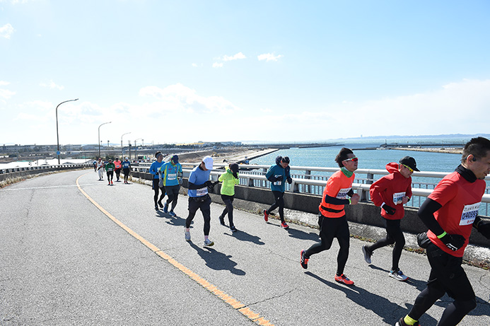 強風のなか一色大橋を走るランナー