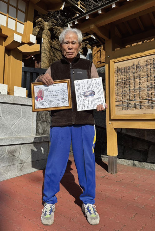 走友たちから贈られた「祝完走100回、190回」の色紙を持つ鈴木さん