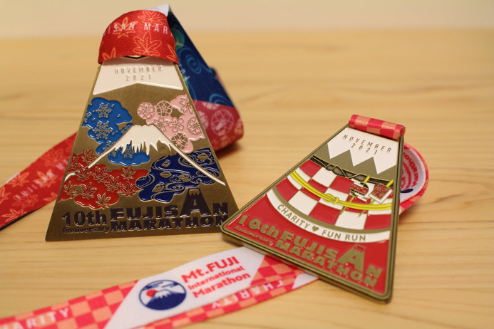外国人ランナーからも大人気の完走メダル。第6回大会から春、夏、秋、冬と季節ごとのモチーフと富士山の組み合わせでしたが、第10回大会は四季が全て盛り込まれたスペシャルデザイン。ひとまわり小さな赤色はチャリティファンランの完走メダル